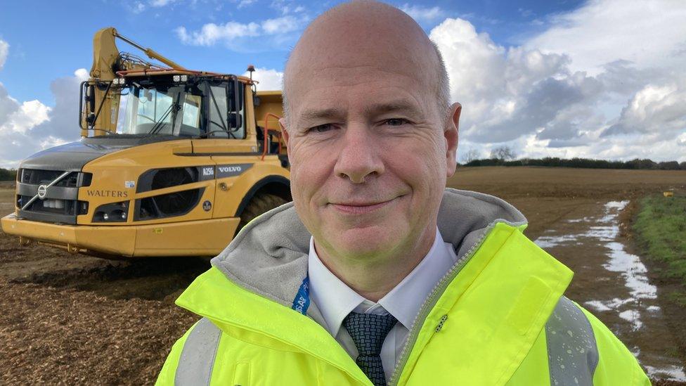 Nick Harris standing next to a digger and wearing a high vis jacket