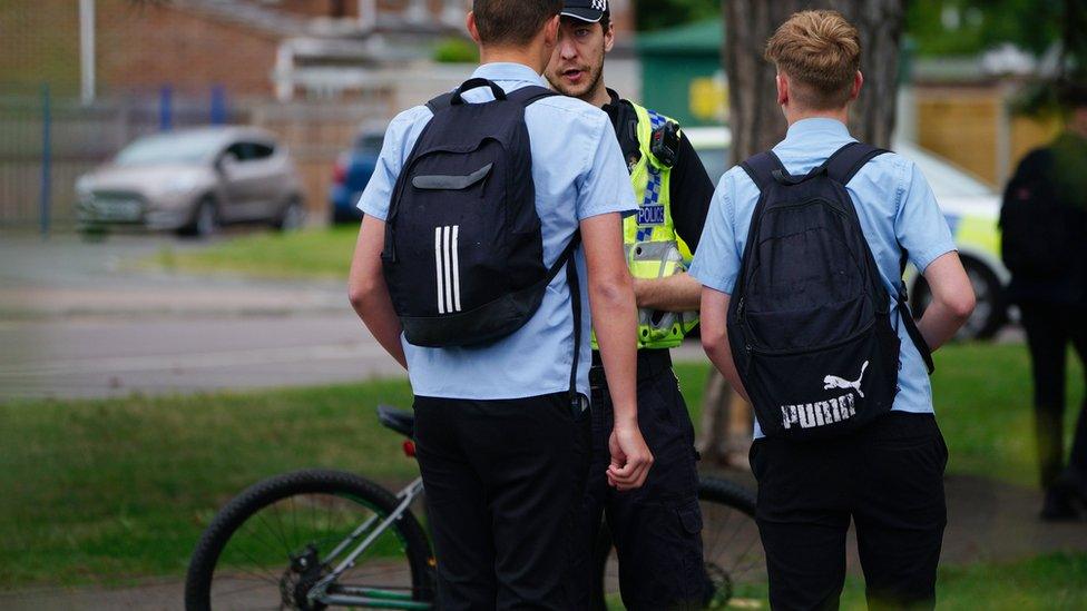 Two male pupils talk to a police officer