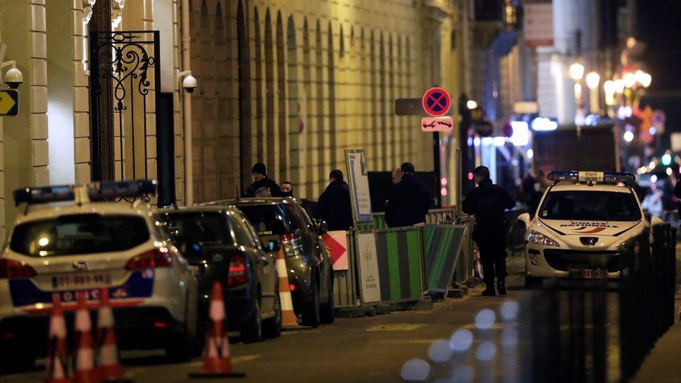 Police guard the hotel's rear entrance on Cambon street