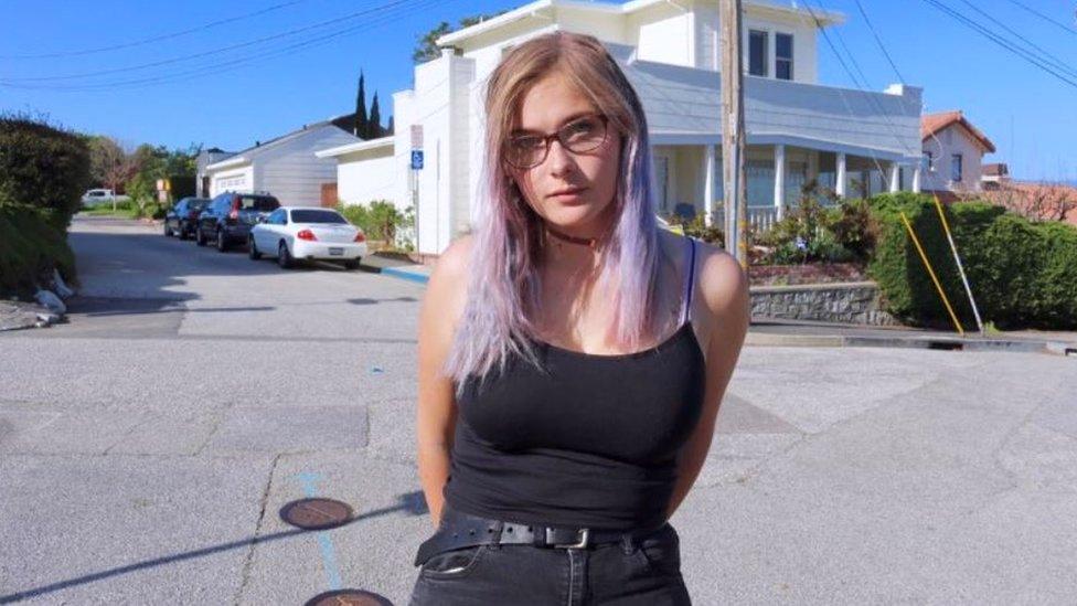 Chrissy poses for a photograph in a sunny residential street