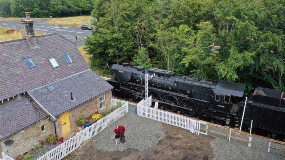 Restored railway station with replica steam train in garden