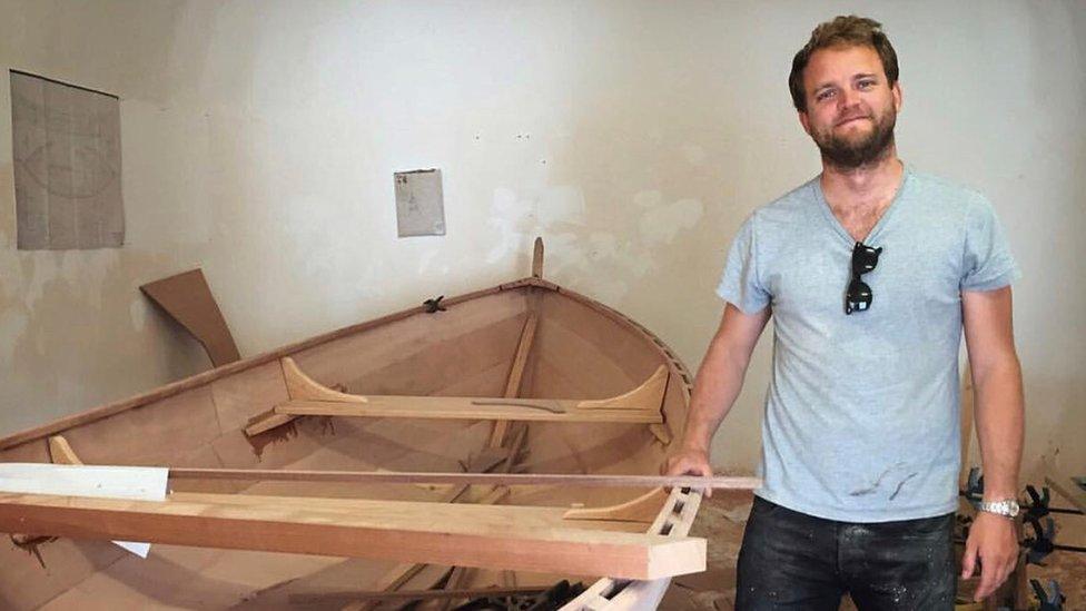 Patrick Wells beside a boat he built