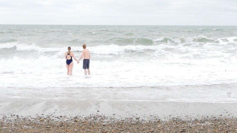 Beth and Andrew walk into the sea