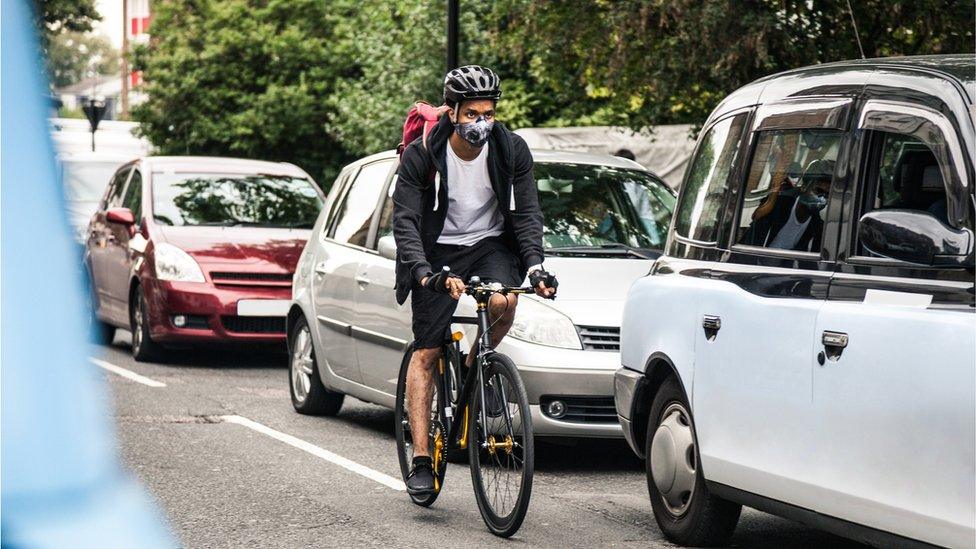 Man cycling past cars