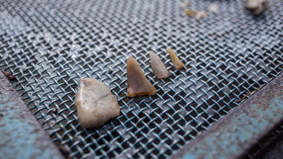 Four small carved artefacts sit on top of a grate