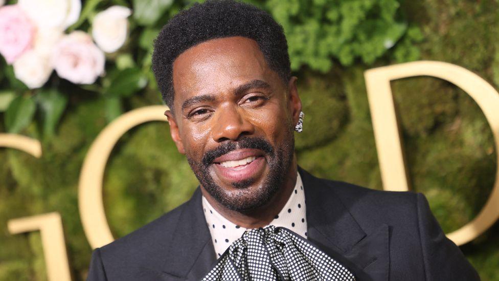 US actor Colman Domingo arrives for the 82nd annual Golden Globe Awards at the Beverly Hilton hotel in LA on 5 January, 2025. He is wearing a black suit, a polka dot shirt and a huge black and white gingham cravat.