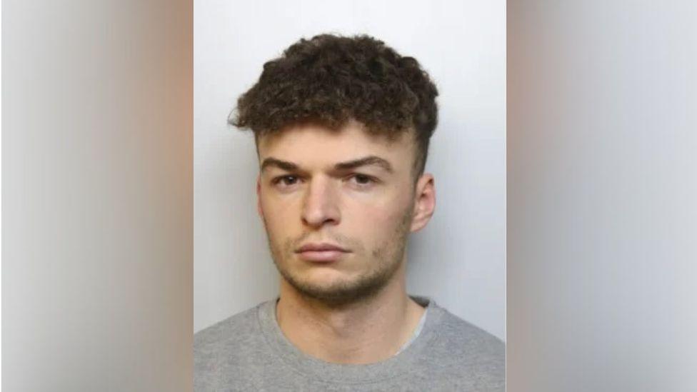 Police image for Manson. He looks into the camera wearing a grey jumper and has brown hair.