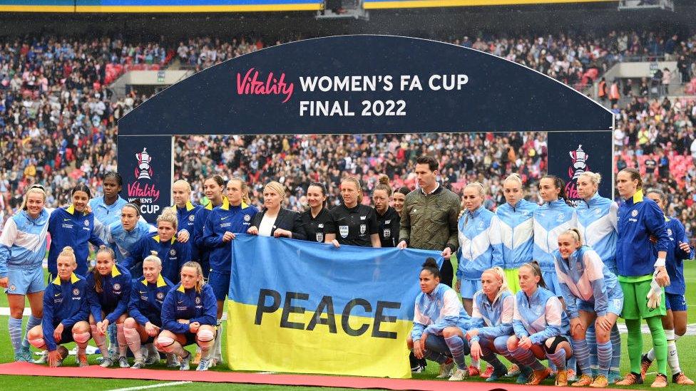 Man City and Chelsea women's players line up ahead of the FA Cup final, they unveil a Ukraine flag with the word peace.