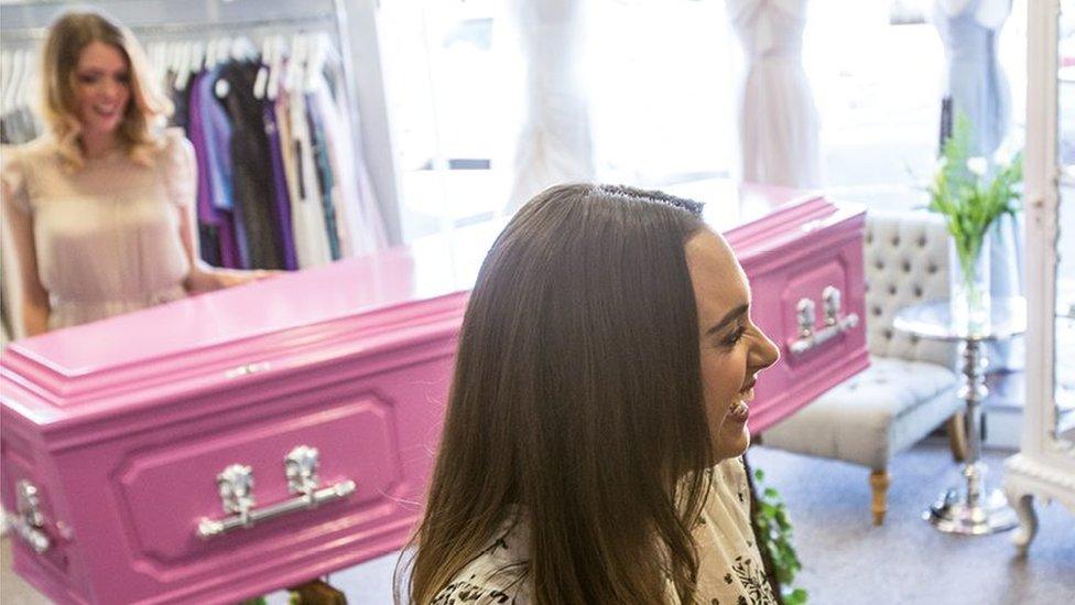 Women shopping for a coffin in what looks to be a wedding dress shop