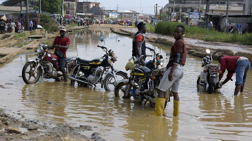 Motorcyclists wash their bikes in the flooded and dilapidated Port Harcourt-Aba highway abandoned by maintenance agencies resulting in an ongoing pro-Biafra protesters agitating for the breakaway of a Biafran state, on November 18, 2015