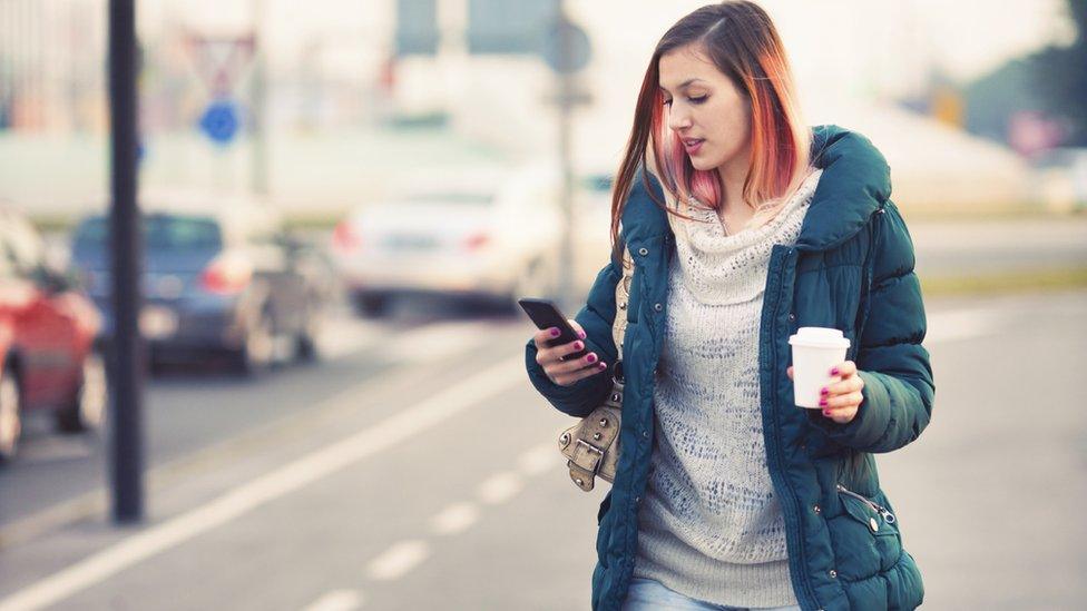 Teenager walking on road, while texting