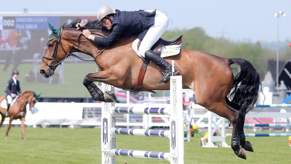 A showjumper and horse jump a fence at Balmoral Show