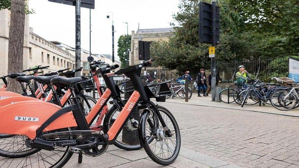 A stock image of electric bikes racked up in a town centre location