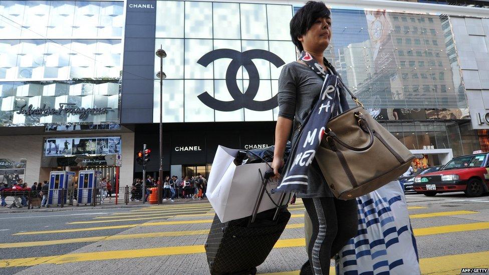 A Mainland Chinese tourist crosses the street carrying multiple shopping bags in the Tsim Sha Tsui region of Hong Kong.