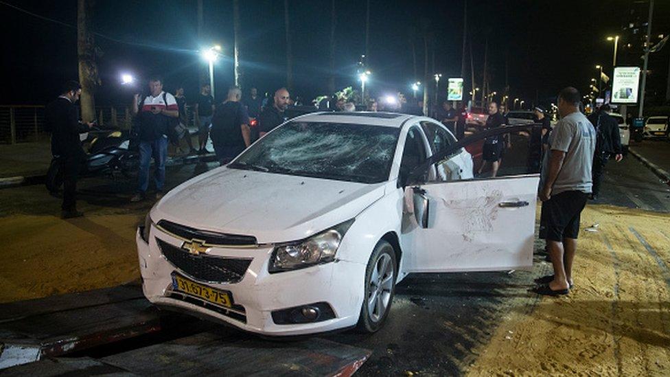 An Israeli man inspects the car of a man who was attacked and injured by a mob in Bat Yam