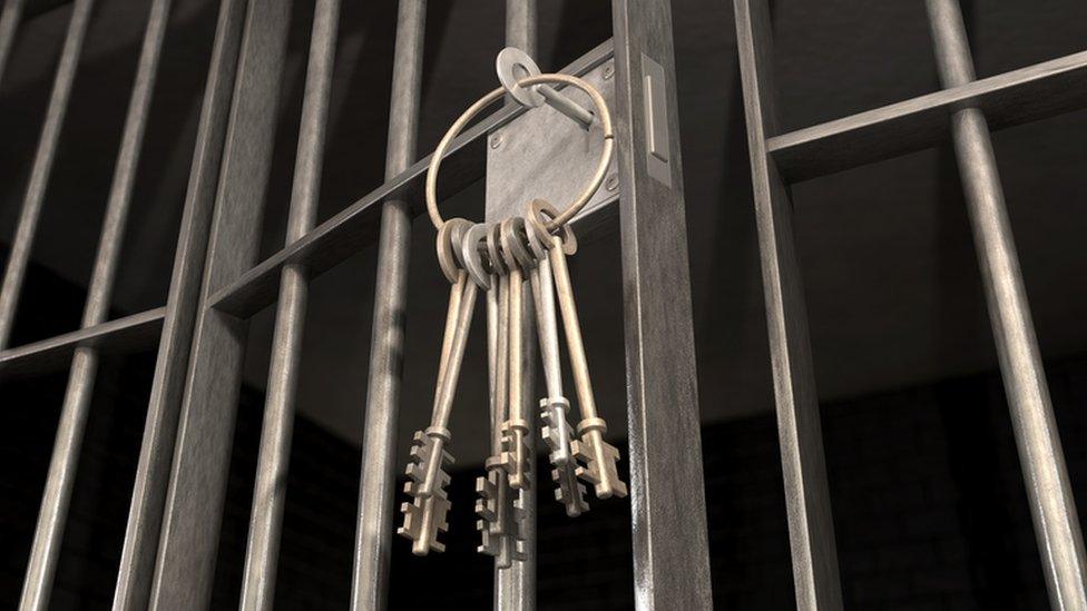 A bunch of keys hanging from a cell door