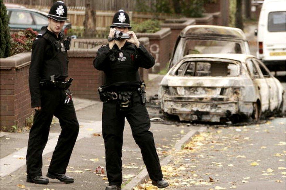 Police investigate the area near burnt out vehicles in Lozells on October 23, 2005 in Birmingham, England