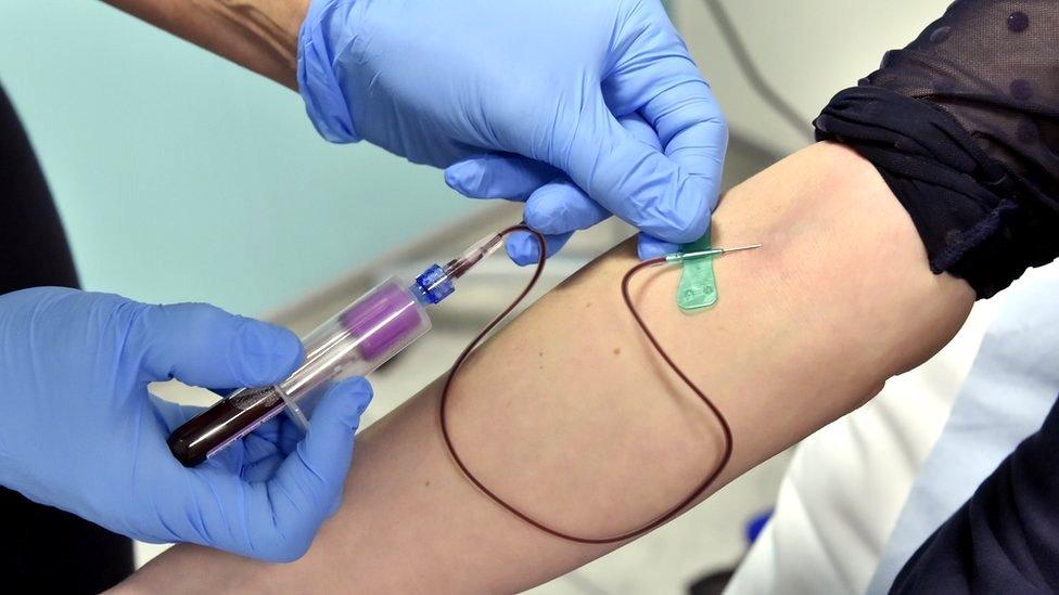 A doctor draws blood from a patient