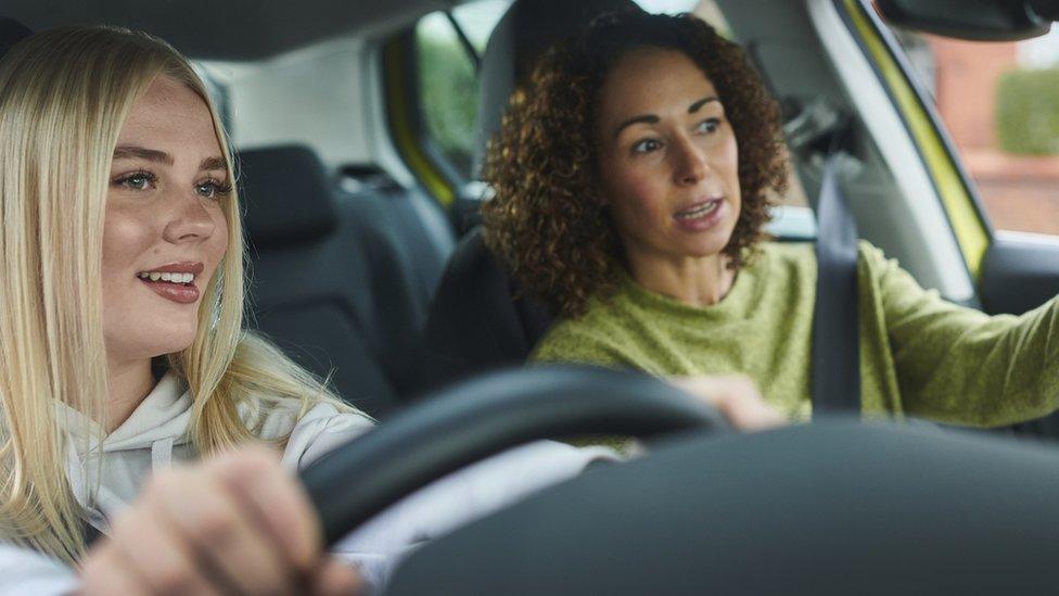 young woman driver getting instructions from older woman