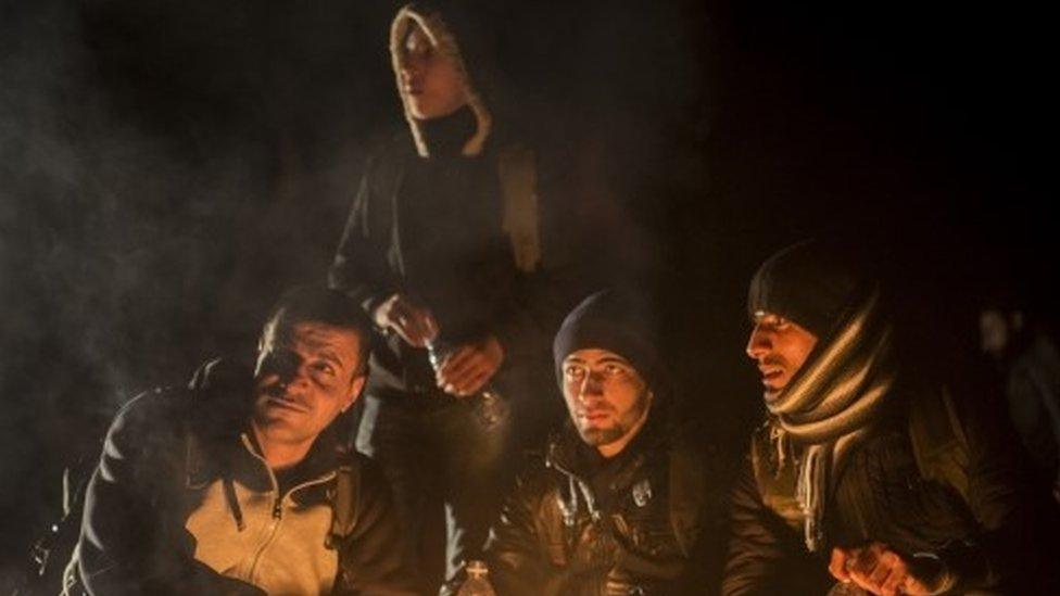 A group of men try to warm up next to a bonfire on a beach shortly after their arrival in a dinghy, with other refugees and migrants, from the Turkish coast to the north-eastern Greek island of Lesbos (30 November 2015)