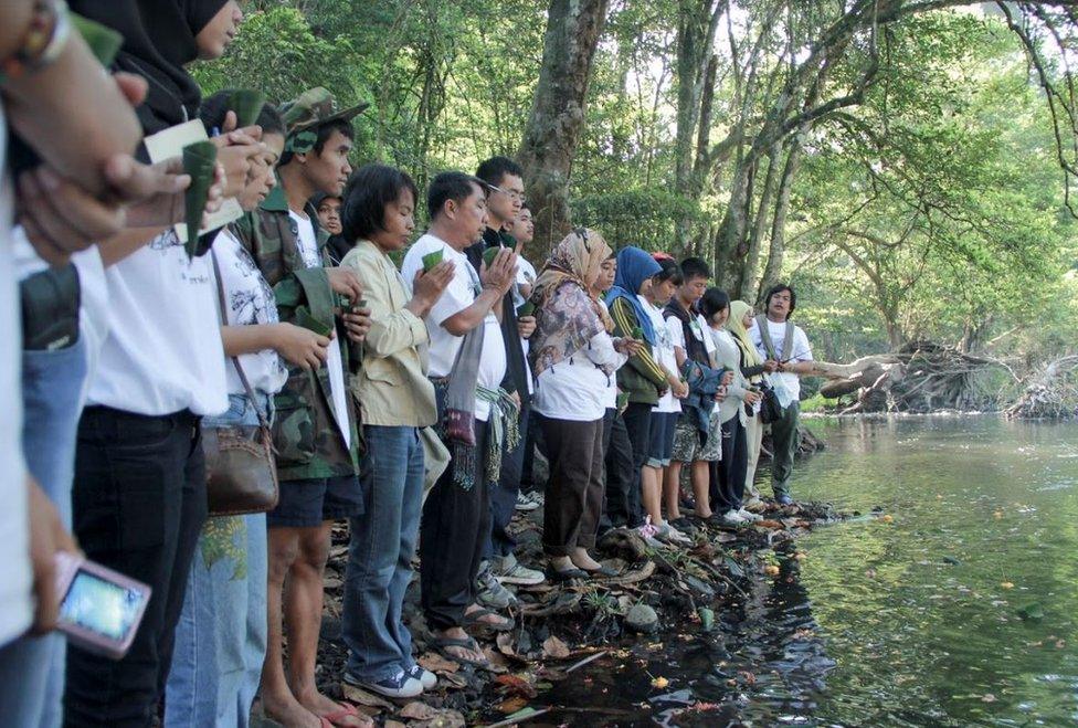 People pray at a riverside memorial service for lost elephants