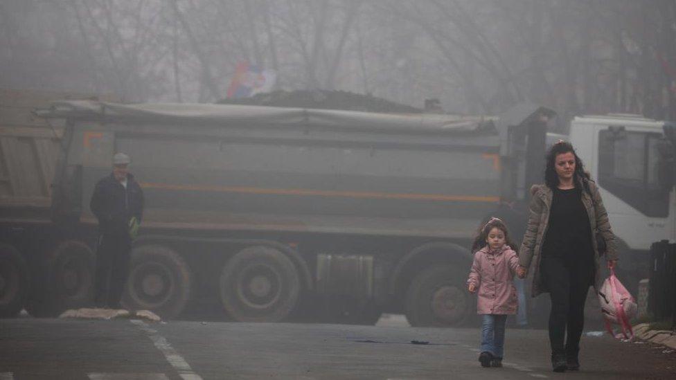 Local Serbs walk near a roadblock, near the northern part of the ethnically-divided town of Mitrovica, Kosovo, December 27, 2022.