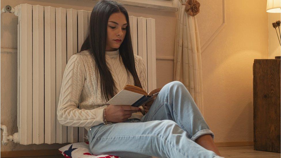 Woman siting with back against radiator