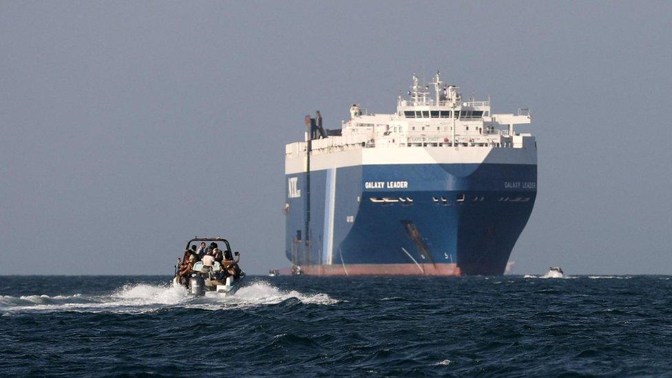 A boat carrying people sails near the Galaxy Leader commercial ship, seized by Yemen's Houthis last month, off the coast of al-Salif, Yemen, December 5, 2023