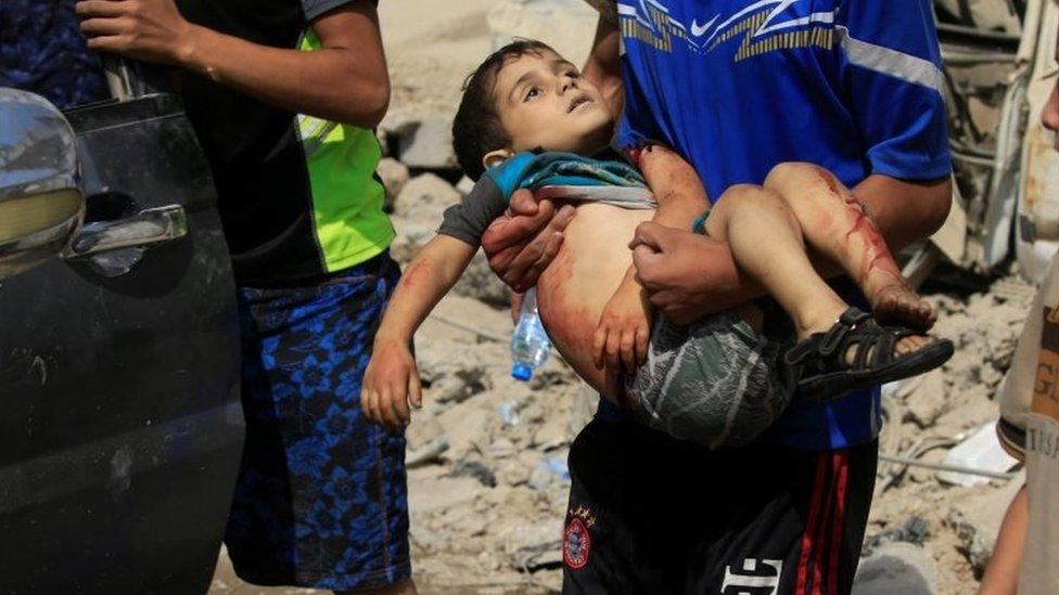 A displaced Iraqi man who fled from clashes, carries a wounded child in western Mosul. Photo: 3 June 2017