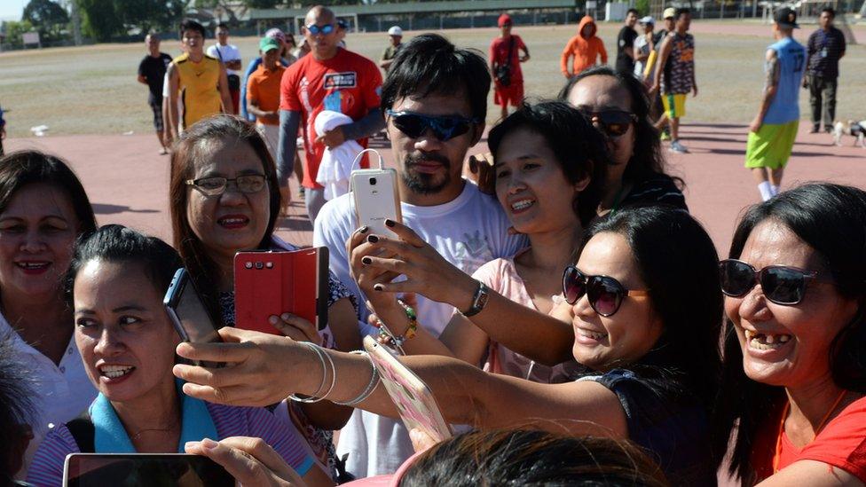 Philippine boxing icon Manny Pacquiao (C) poses for photos with visitors in General Santos City, in southern island of Mindanao on February 19, 2016