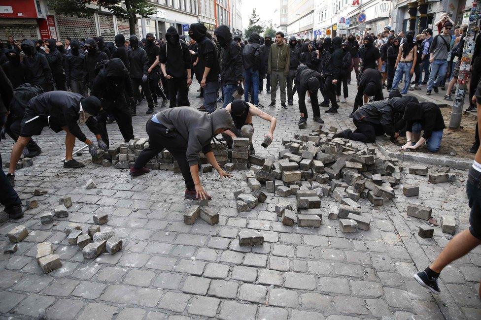 Protesters dig up paving stones to throw at police on July 7, 2017