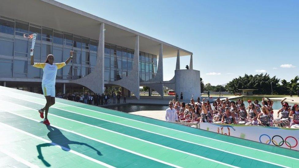 Brazilian volleyball player Fabiana Claudino holds the Olympic torch after receiving it from Brazilian President Dilma Rousseff at Planalto Palace in Brasilia following the flame's arrival in Brazil on May 3, 2016,