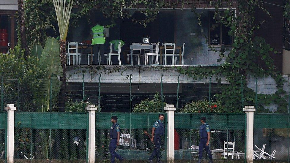 Policemen patrol outside the Holey Artisan Bakery and the O'Kitchen Restaurant as others inspect the site after gunmen attacked, in Dhaka, Bangladesh