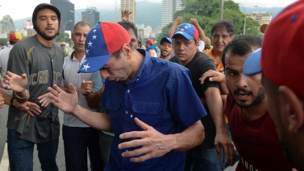 Opposition leader Henrique Capriles reacts to tear gas