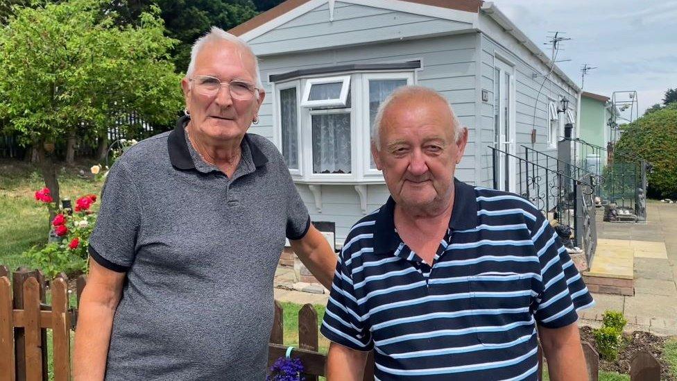 Chris Murphy, wearing a blue striped t-shirt, has white hair and earrings. He is standing next to his friend Gordon Pick who is wearing a blue and white striped t-shirt.