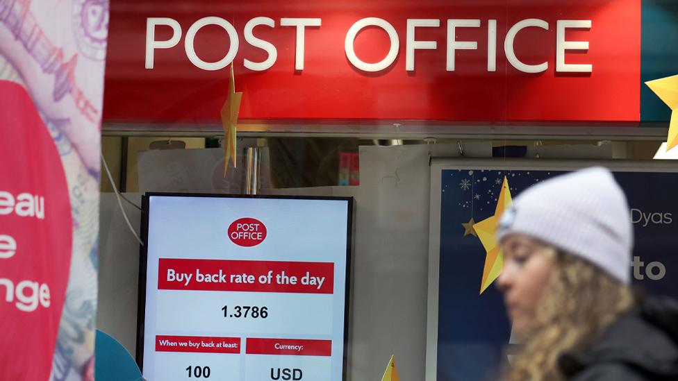 Woman walks in front of Post office branch