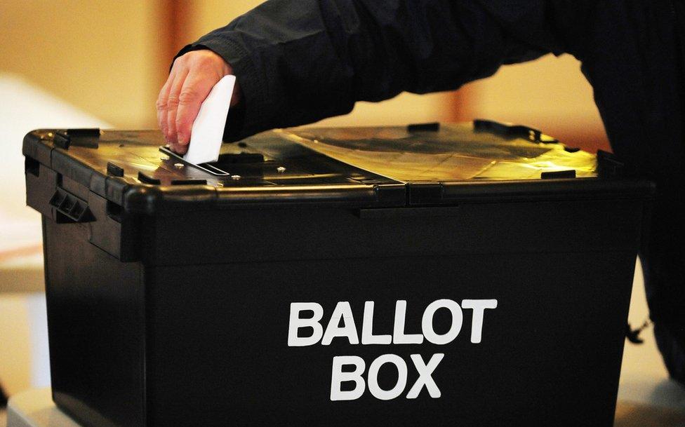 A man putting a ballot paper into a ballot box