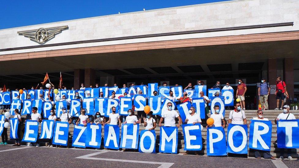 Cruise industry workers stage a protest with signs calling for an "Immediate solution for Venice's home port".