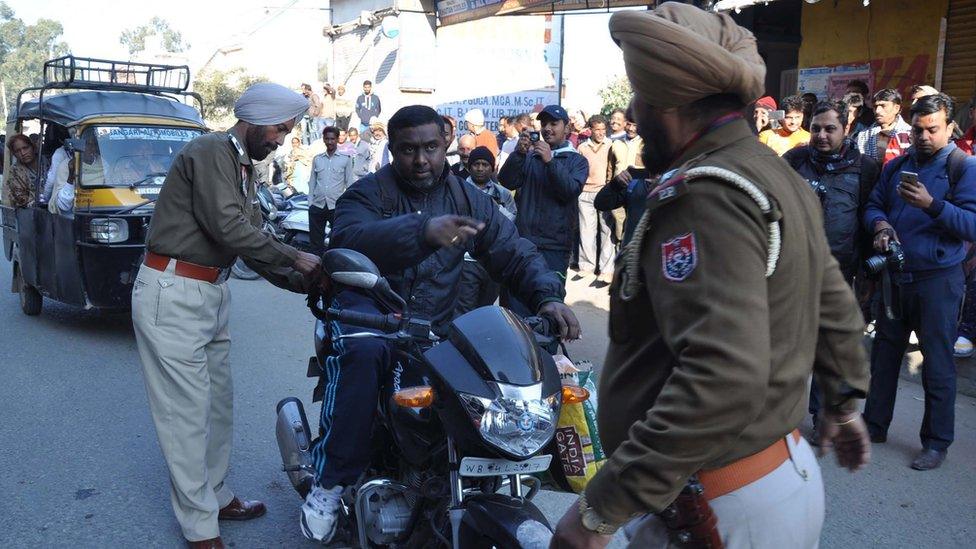 Indian police search a motorcyclist in Punjab state