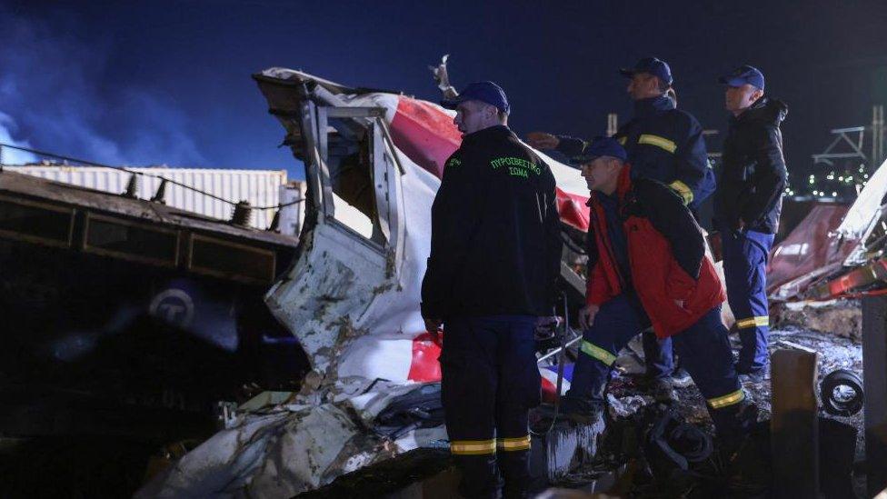 A group of firefighters look at the crushed carriage