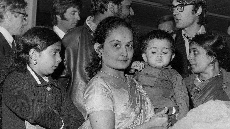 Asian women, one holding a child, arrive in London after the forced expulsion of minorities from Uganda