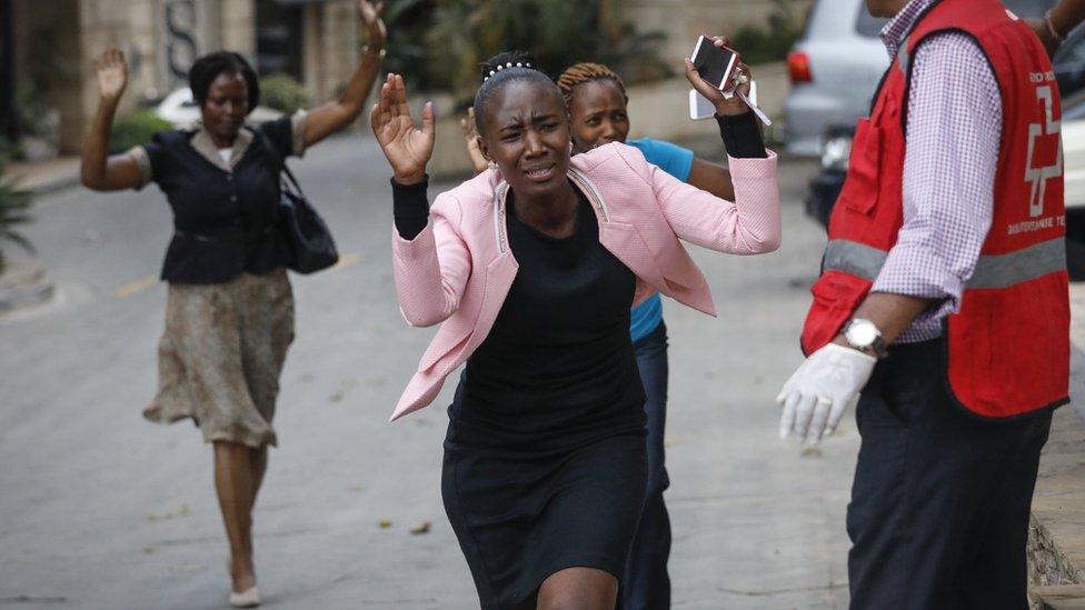 Women raise their hands as they make a run for the rescue workers during an ongoing gunfire and explosions in Nairobi, Kenya, 15 January 2019.