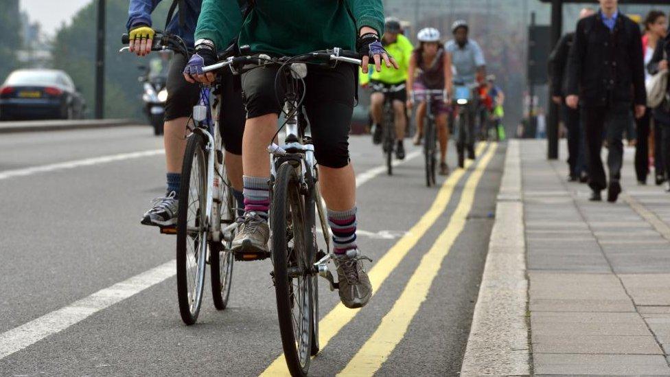 People cycling down a road in London