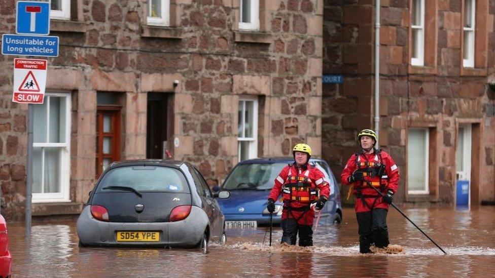 Firemen walk through floodwater on the High Street in Stonehaven