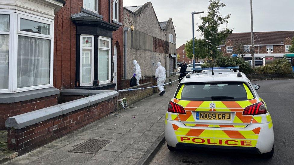 Parked police car with forensics officers