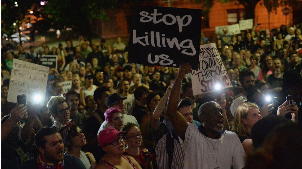 Hundreds of protestors gather holding signs including "stop killing us" in St Louis and "black lives matter"