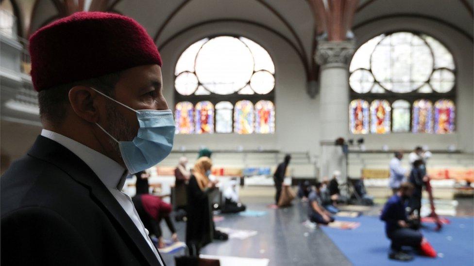 A Muslim man wearing a face masks prays at a church in Berlin