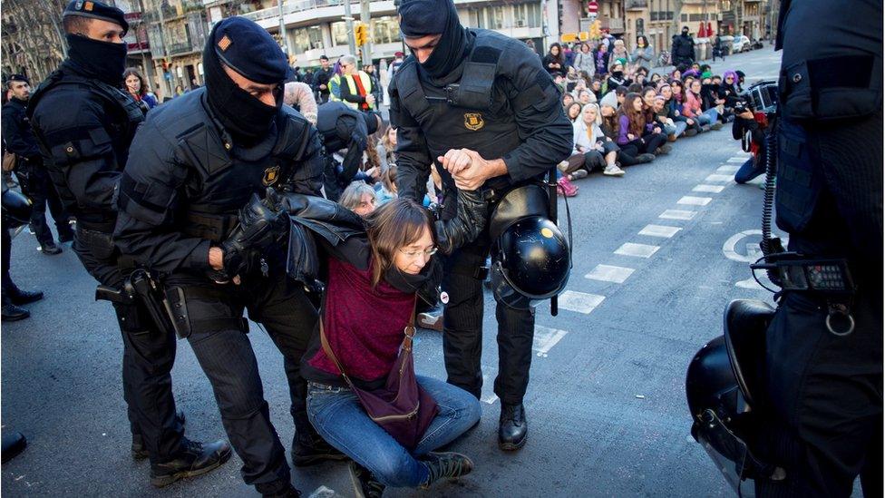 Officers of Mossos d'Esquadra, the Catalan regional police, remove women who block the Gran Via avenue during a sit-in protest in Barcelona