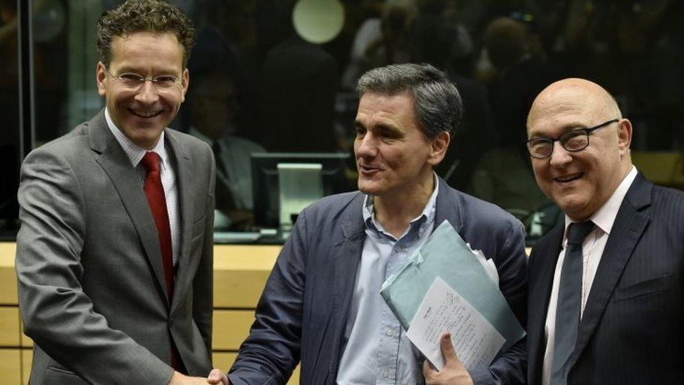 Dutch Finance Minister and president of the Eurogroup Jeroen Dijsselbloem (L) shakes hands with newly appointed Greek Finance Minister Euclid Tsakalotos (C) as French Economy, Finance and Trade Minister Michel Sapin (R) looks on during a Eurogroup meeting ahead of a Eurozone Summit meeting at the EU headquarters in Brussels 7 July 2015