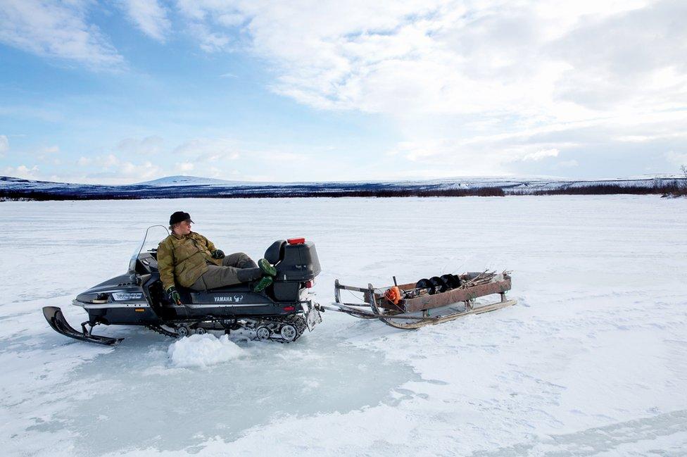 A man sits on his snowmobile.